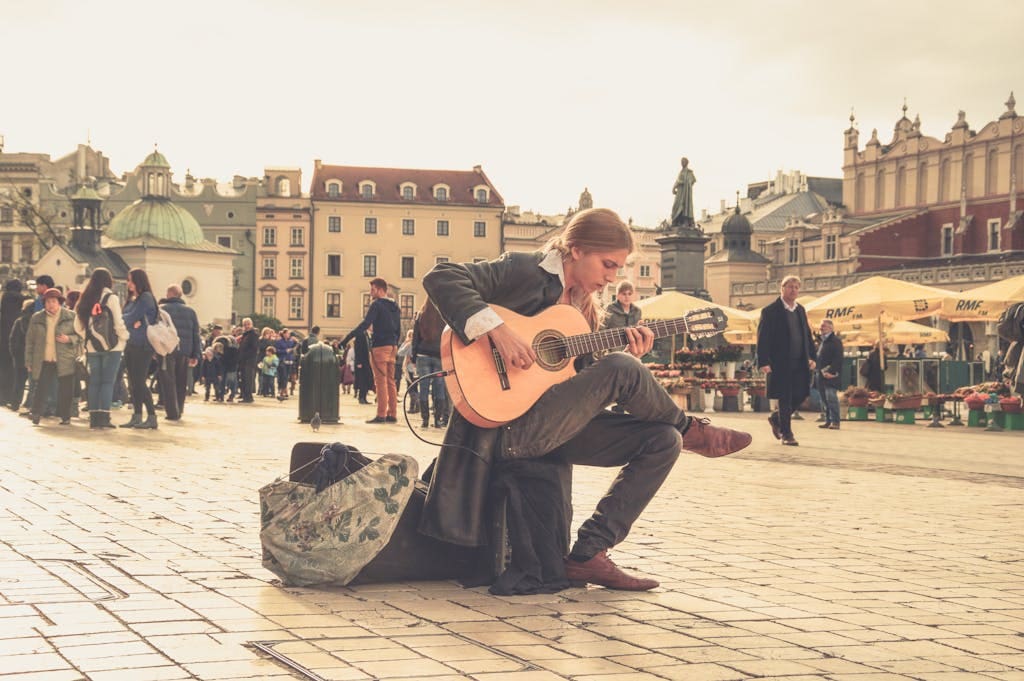 A street performer playing guitar in a vibrant old town square with a lively crowd.