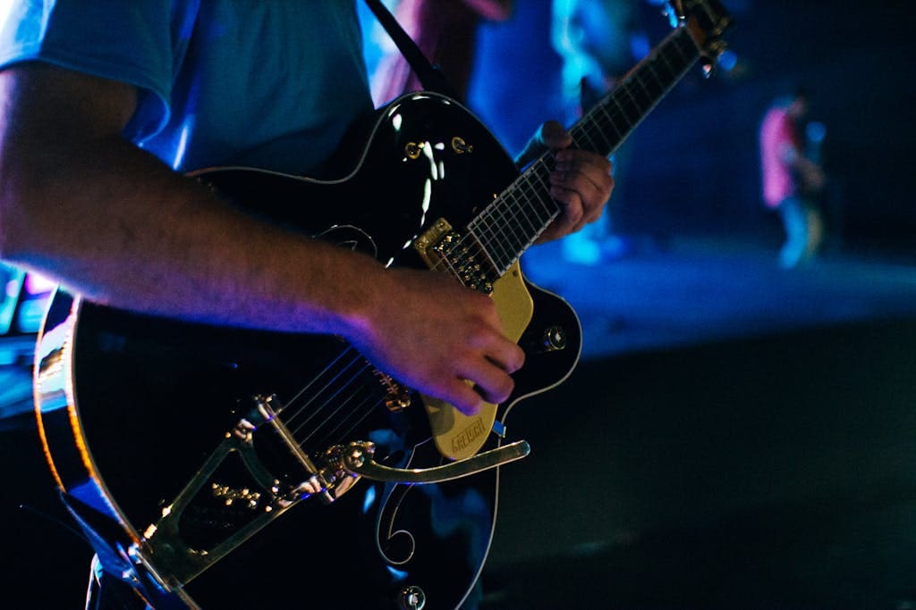Close-up of a guitarist playing electric guitar on stage, vibrant night scene.