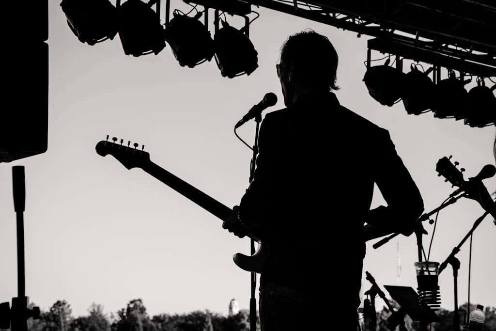 Silhouette of a guitarist performing at an outdoor concert, capturing musical essence.
